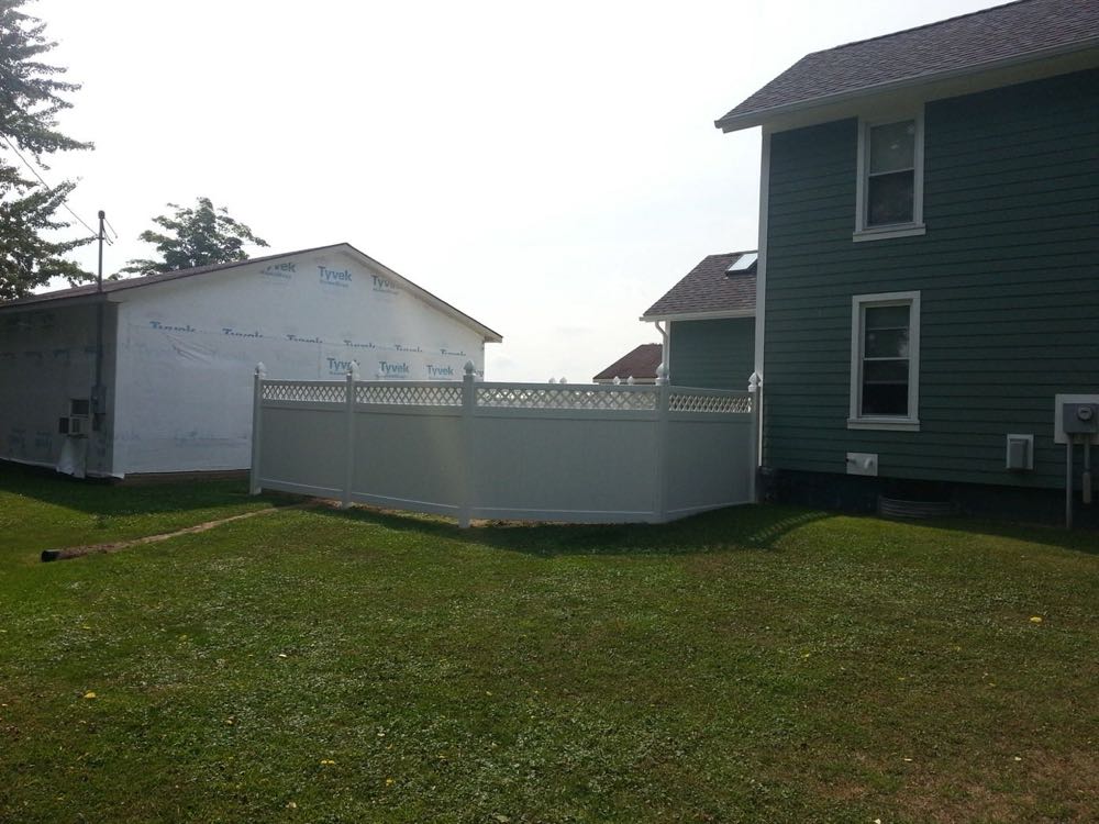 Tan vinyl privacy fence beside a house