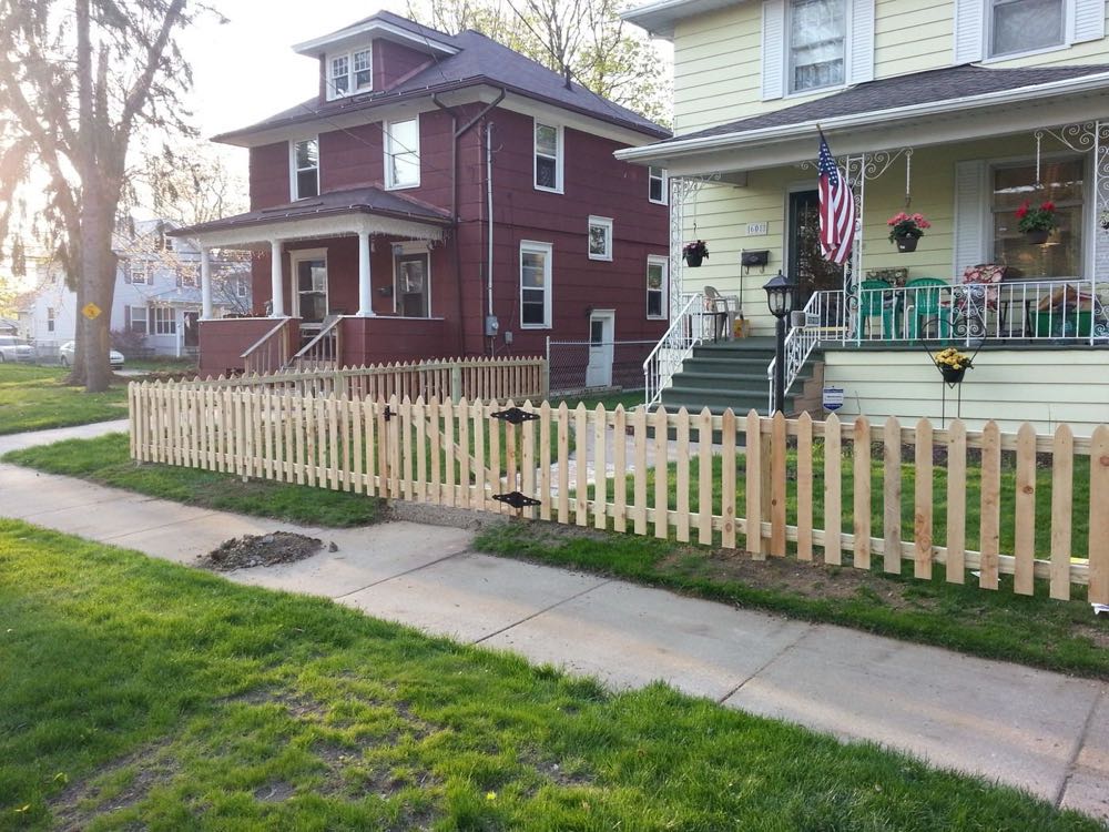 Wood picket fence in front of a brick home
